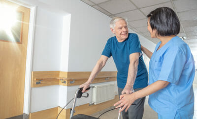 Asian female doctor reassuring mature elderly man with walker. M