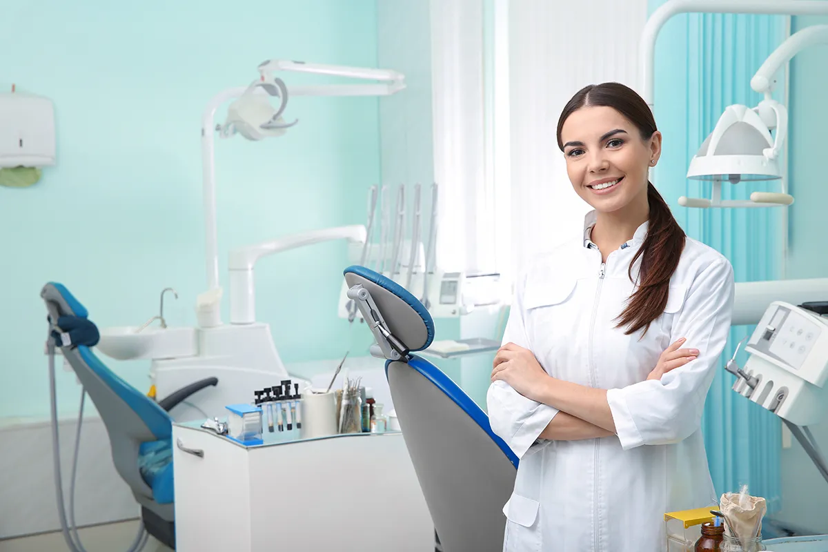 Odontóloga posando y sonriendo en un consultorio dental.